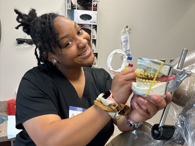 student posing with a dental mold for assistant training